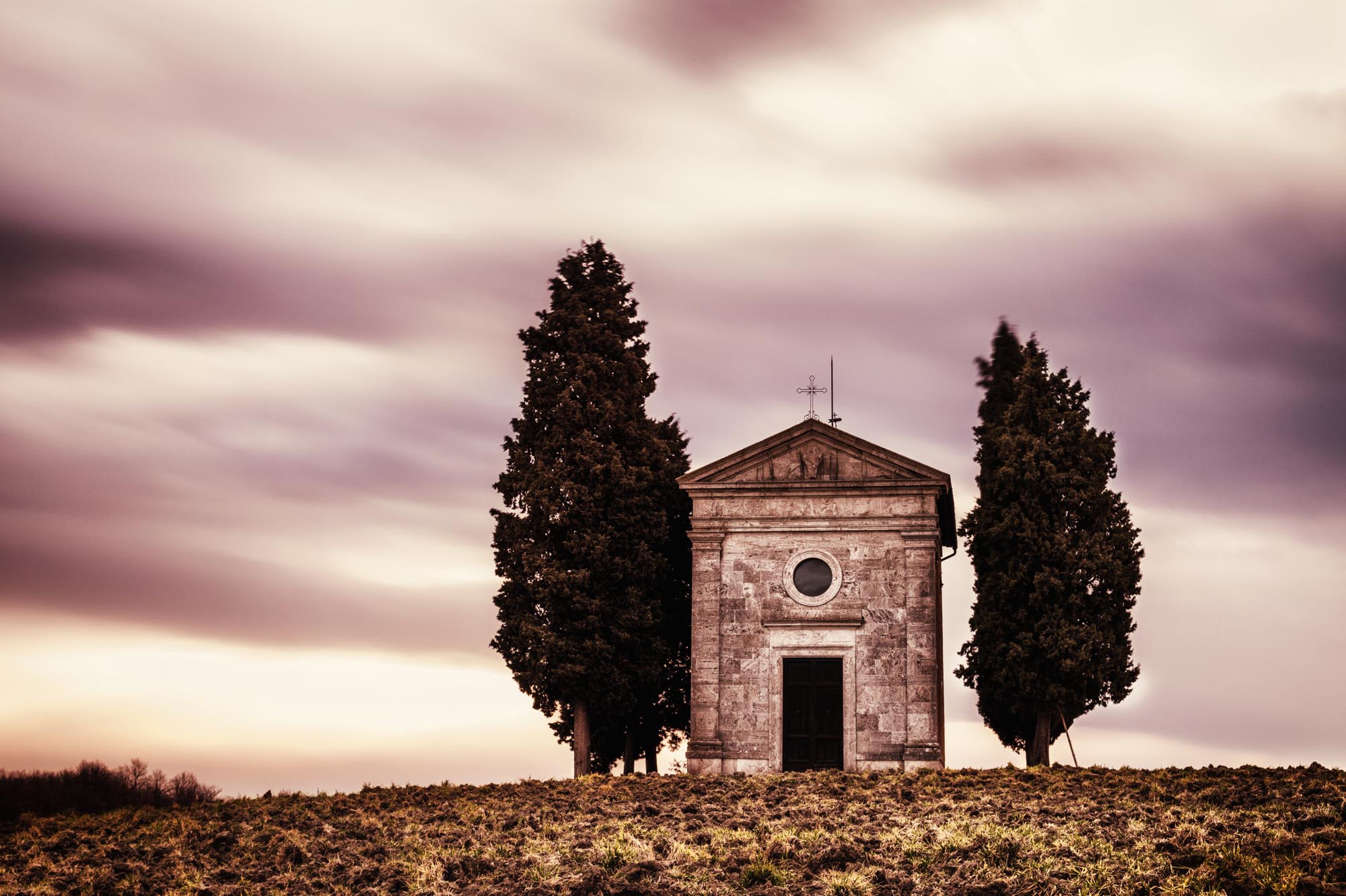A small italian chapel with cypresses